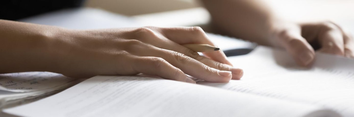 Närbild på två händer som ligger på en bok.
